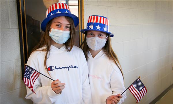 Two girls smile while dressed as voting volunteers